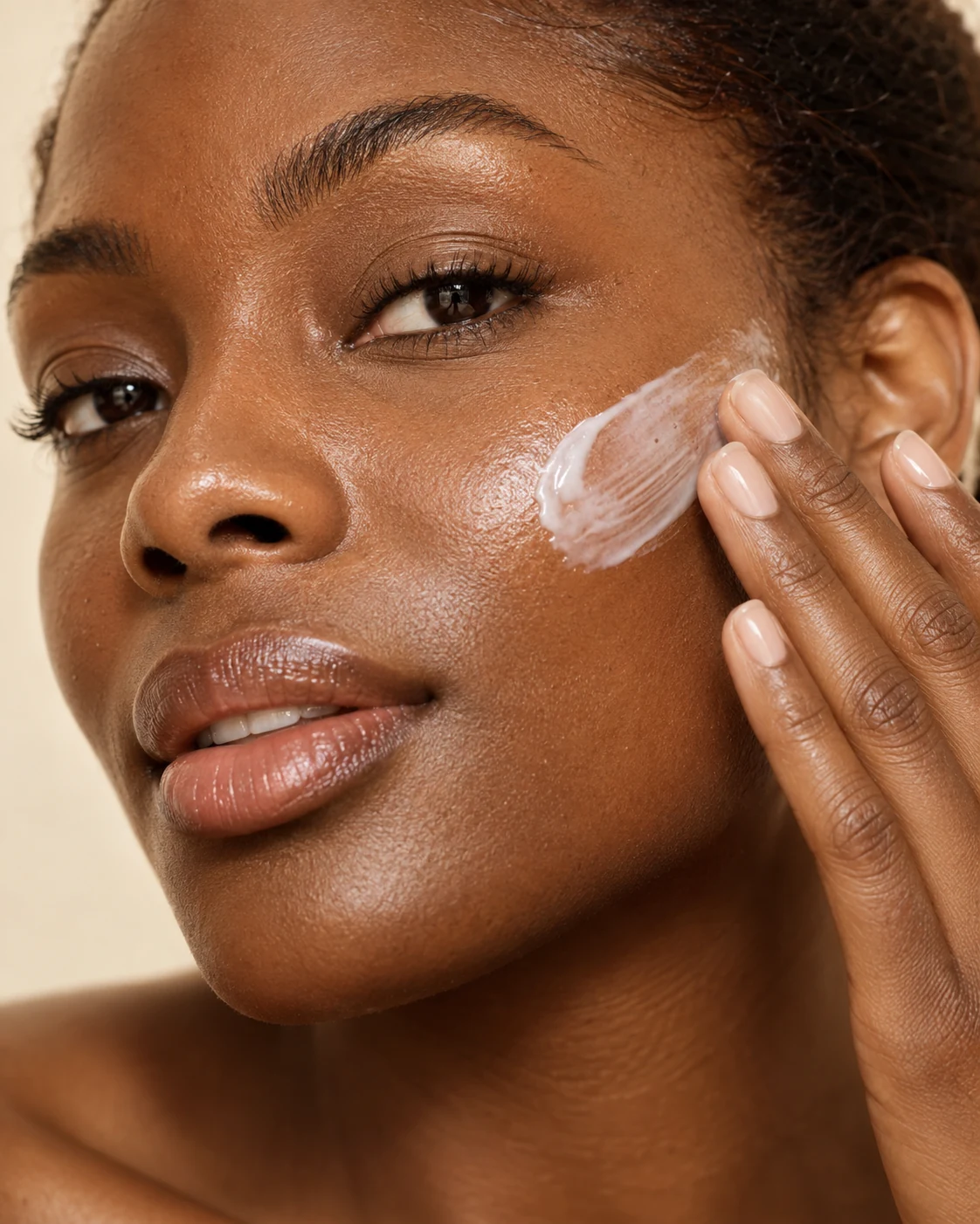Close-up of a client applying moisturizer to her cheek